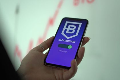 Mão segurando um smartphone com uma carteira digital de criptomoedas exibida na tela