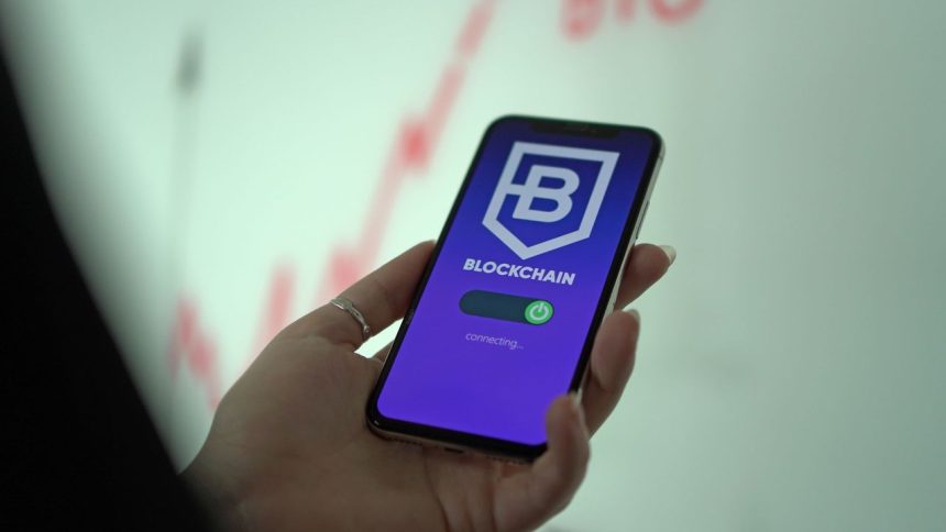 Mão segurando um smartphone com uma carteira digital de criptomoedas exibida na tela