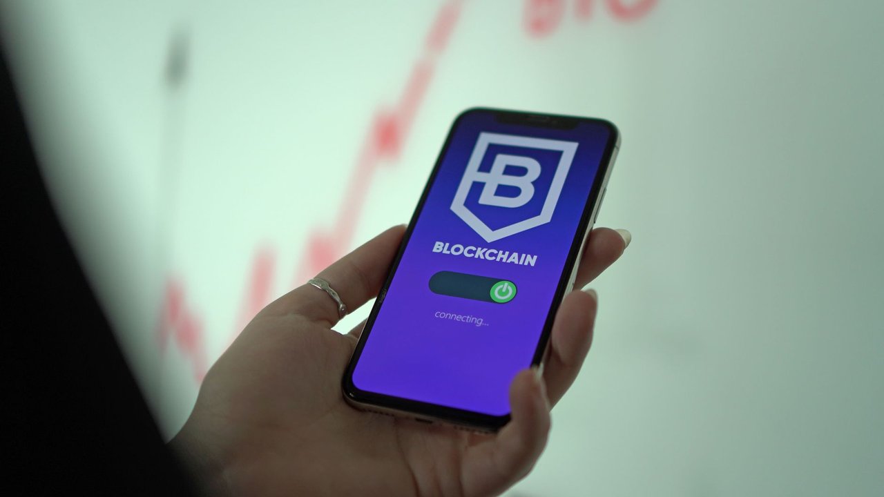 Mão segurando um smartphone com uma carteira digital de criptomoedas exibida na tela