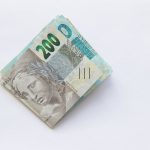 Pilha de cédulas de 200 reais brasileiras sobre uma superfície branca.