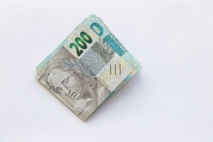 Pilha de cédulas de 200 reais brasileiras sobre uma superfície branca.
