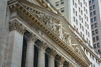 Fachada da Bolsa de Nova York, em Manhattan, com colunas clássicas e bandeiras dos Estados Unidos