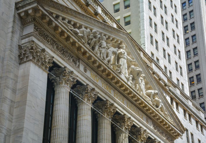 Fachada da Bolsa de Nova York, em Manhattan, com colunas clássicas e bandeiras dos Estados Unidos