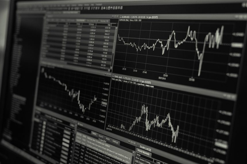 Monitores exibem gráficos e dados de mercado financeiro em preto e branco.